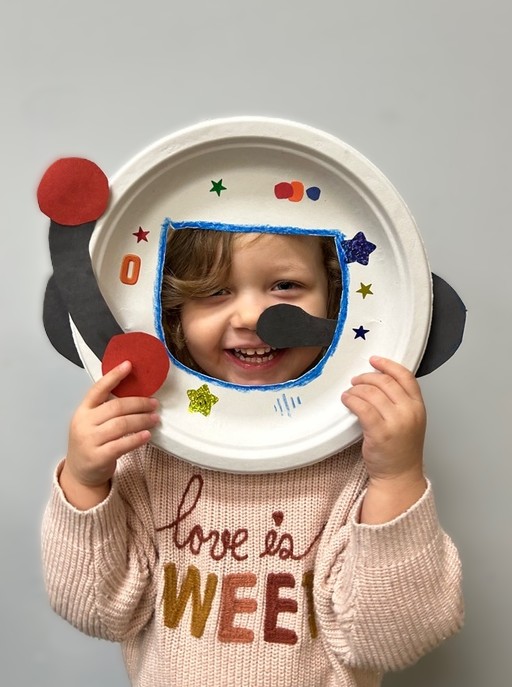 Child holding handmade astronaut helmet craft