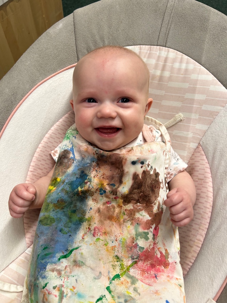 Baby laughing with paint covered apron
